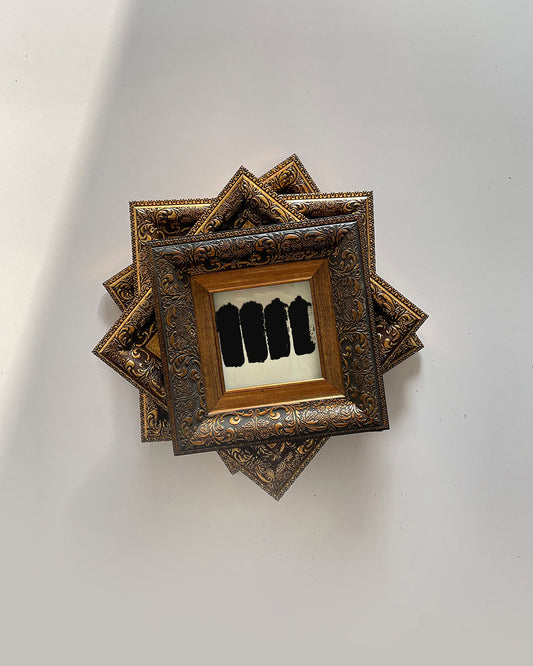 GOLD STAIN wall art in decorative wooden frame on white wall